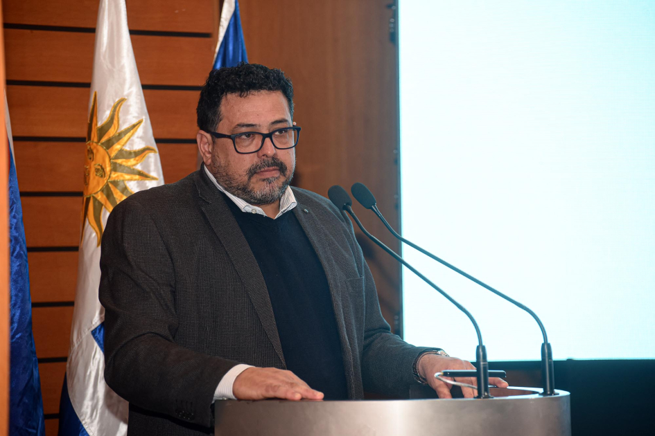 Sánchez habla desde una tril; detrás, bandera uruguay