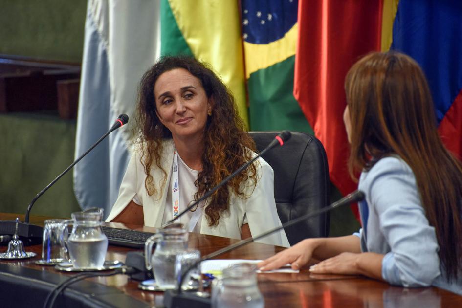 Directora ejecutiva de Uruguay Innovation Hub, Sabrina Sauksteliskis Sabrina Sauksteliskis, de frente y con banderas atrás, dialoga con la moderadora, de espaldas