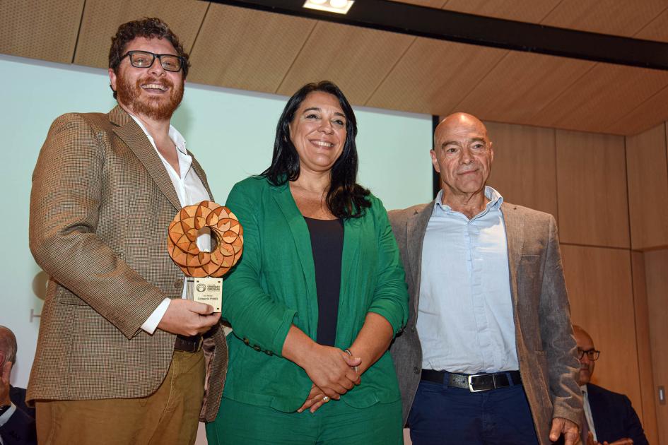 En el centro, Carmen Sánchez, junto a dos hombres; uno sostiene el premio (que tiene forma similar a