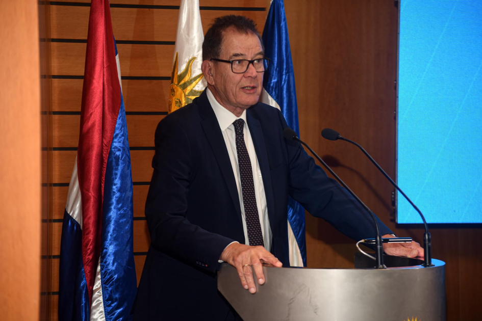 Director general de la ONUDI, Gerd Müller Müller habla desde un atril; detrás, banderas