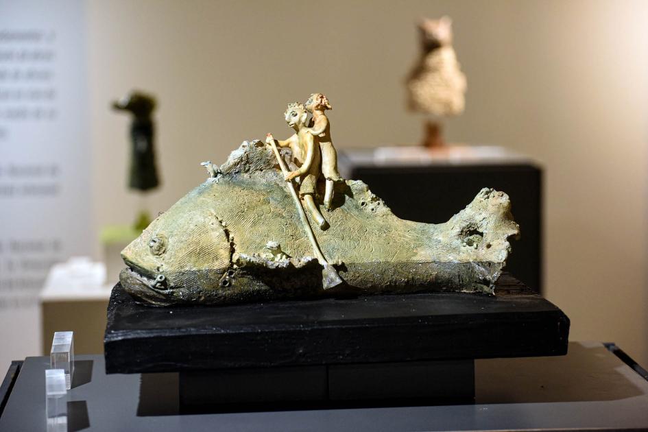Artesanía premiada Pieza en la que se ve un pez con dos figuras; una rema sobre él