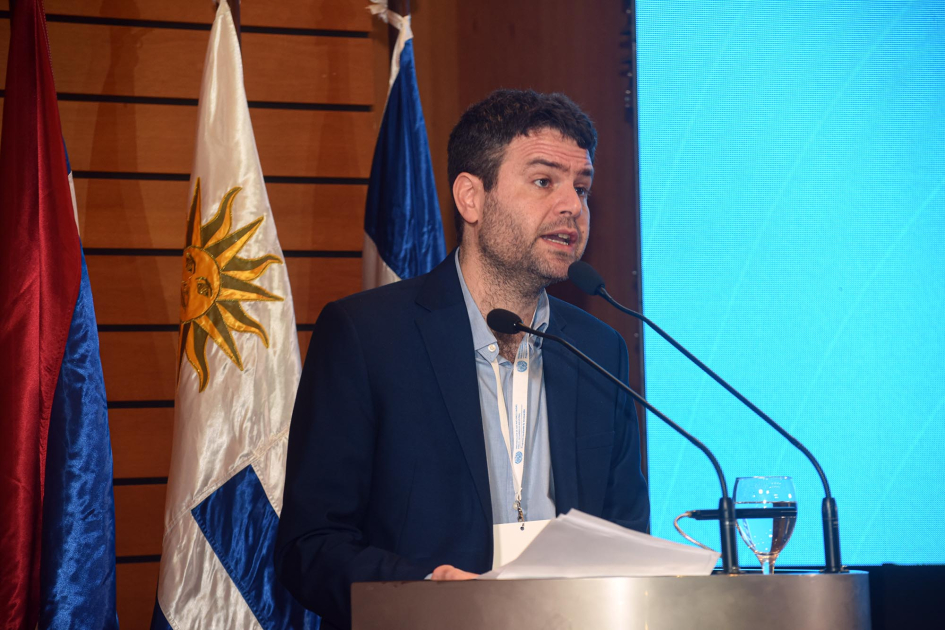 Daniel Schteingart, de Argentina, 'keynote speaker' del evento Schteingart habla desde un atril; detrás, banderas