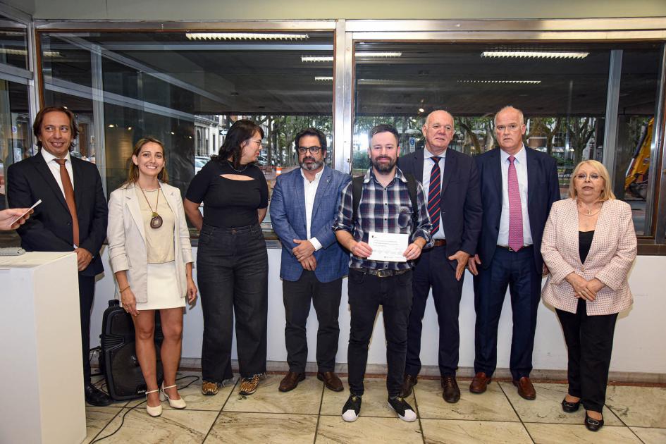 Mención del concurso de afiches: Héctor Leonardo Rodríguez Autoridades con un hombre que sostiene un papel