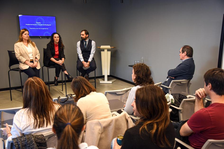 Directora ejecutiva de Uruguay Innovation Hub, Sabrina Sauksteliskis Sauksteliskis habla a la audiencia, que se ve de espaldas; a su lado, Martínez y Varela