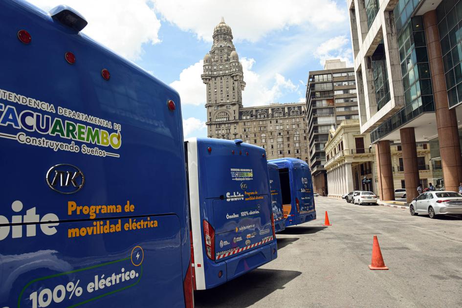 La compra de los ómnibus recibió un fuerte apoyo del programa Subite Buses de la DNE del MIEM Ómnibus vistos de atrás; al fondo, el Palacio Salvo