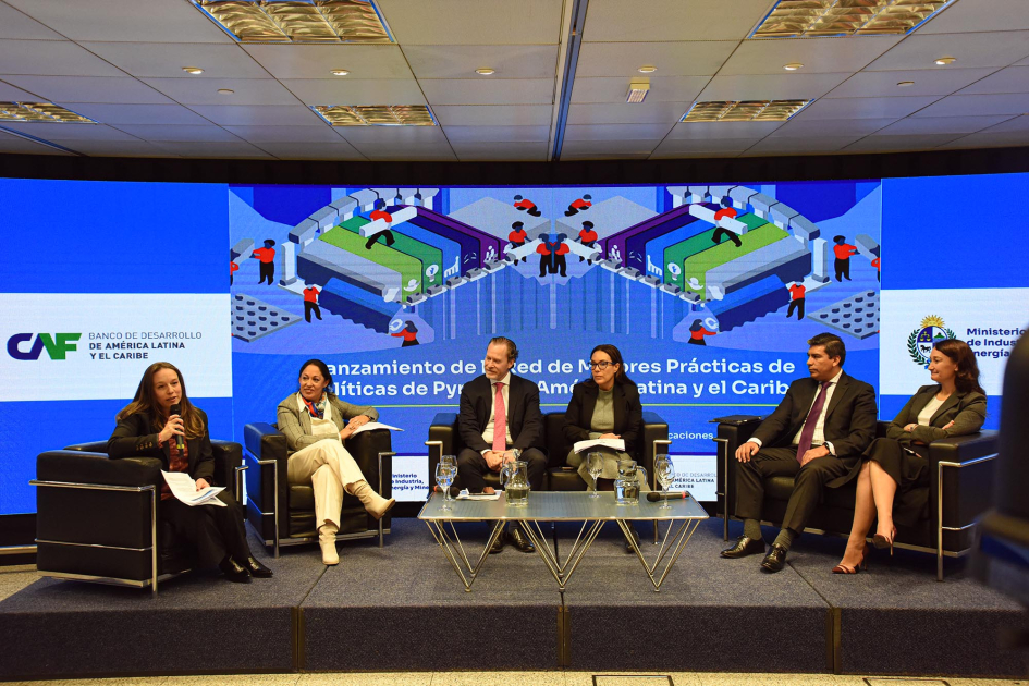 Panelistas, sentados; detrás, pantalla