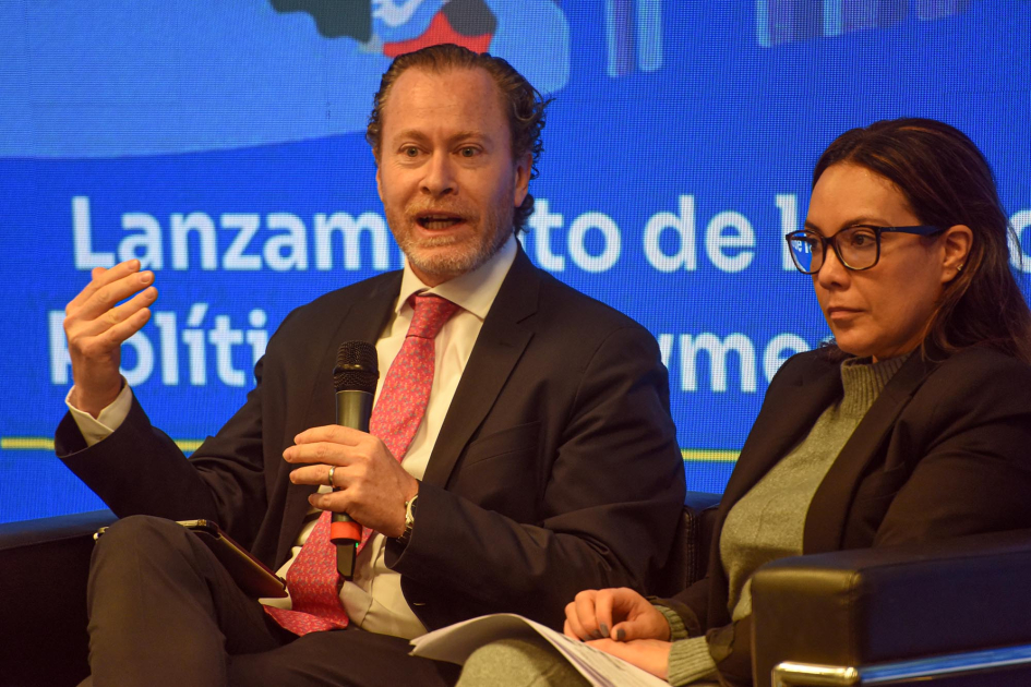 Ardaví habla, sentado junto a otra panaliesta; detrás, pantalla