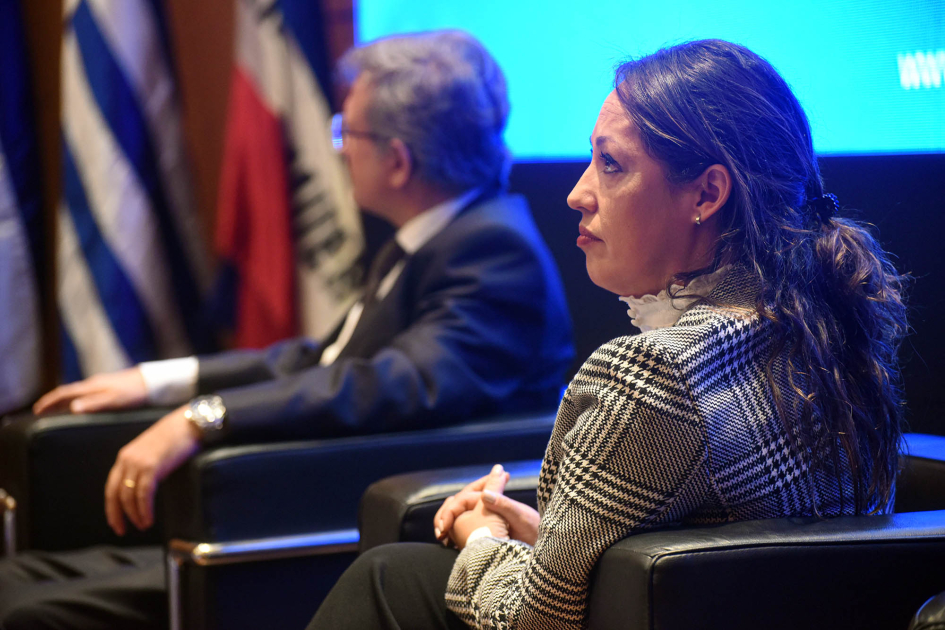 Apertura del evento Cardona, sentada de perfil, junto a Scottelaro; al fondo, banderas