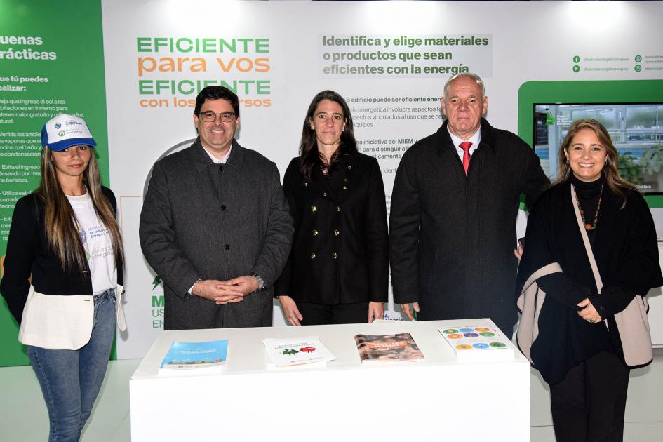 Autoridades del MIEM posan en el stand de la institución junto a una promotora