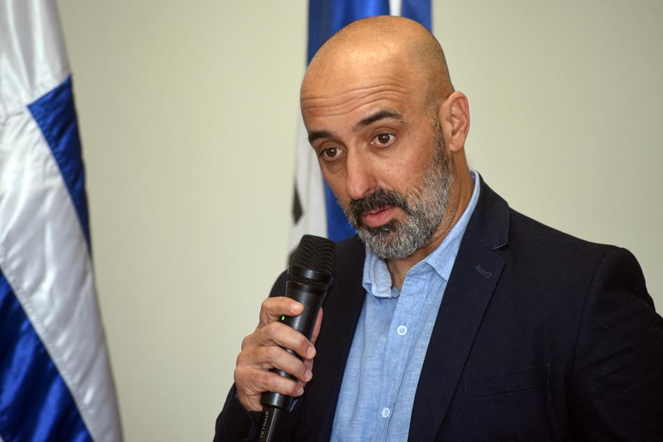 Presidente de la Asociación de Mineros de Artigas, Carlos Sanchís Sanchís habla con un micrófono; detrás, pabellones