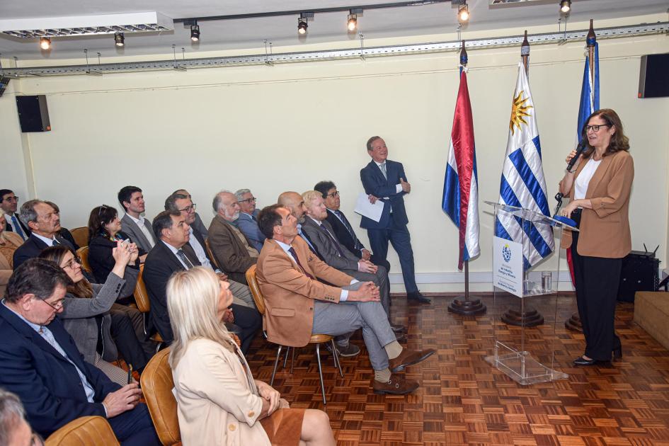Ministra Elisa Facio Ministra habla ante el público; a su lado, pabellones patrios