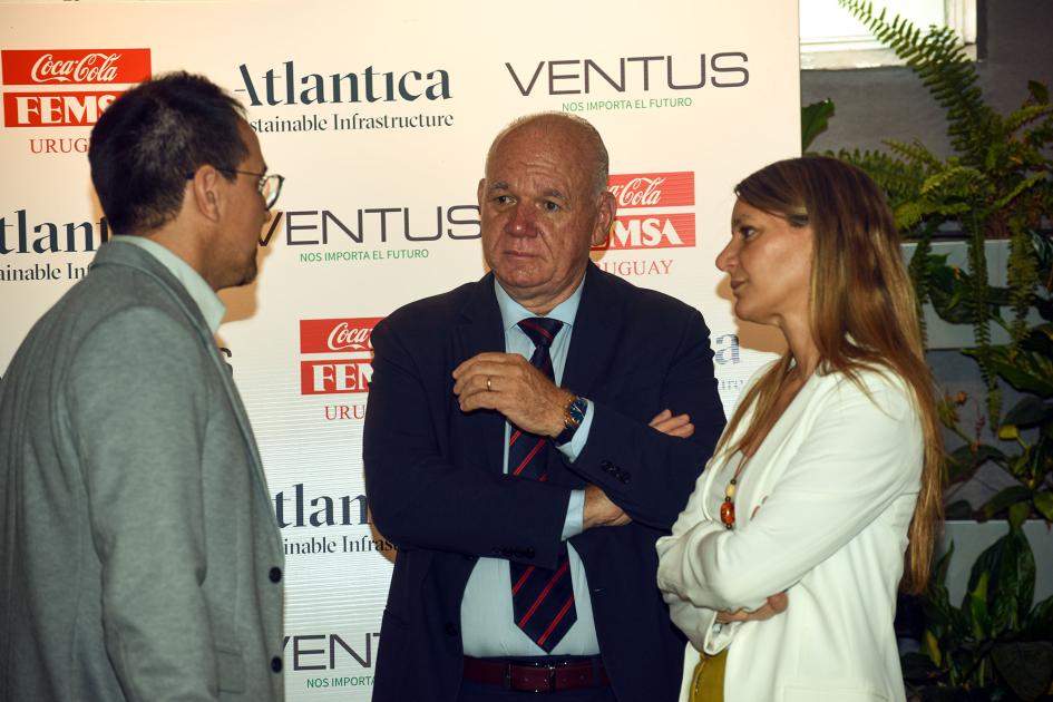 El subsecretario Walter Verri participó el evento Verri dialoga con un hombre y una mujer; detrás hay un banner con los nombres de las empresas
