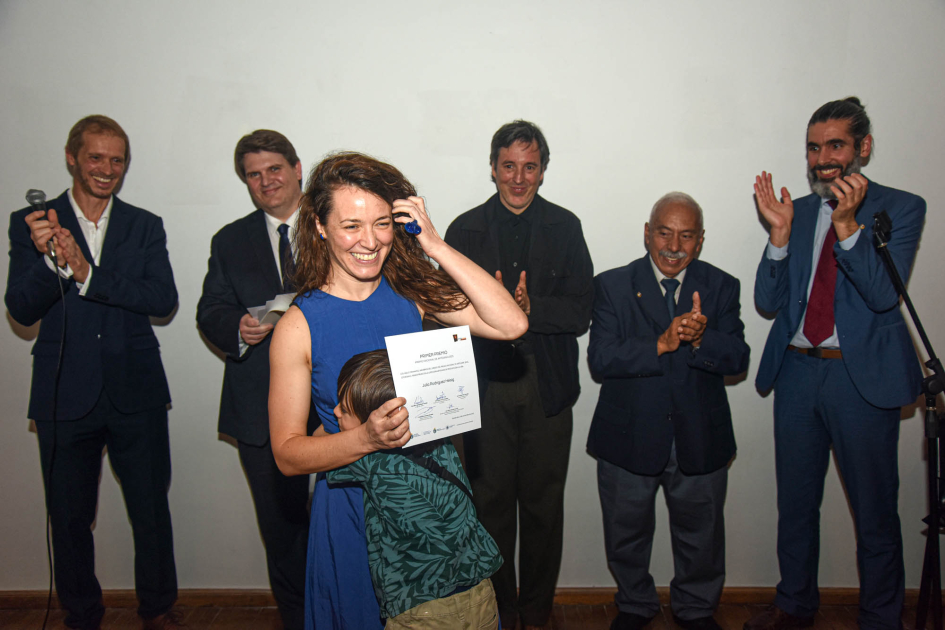 Julia Rodríguez Heisig (primer premio en Artesanía de producción) Artesana sostiene diploma, abrazada por un niño; detrás, autoridades