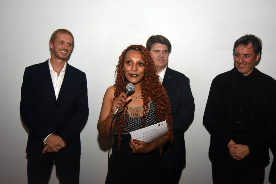 Silvana Ríos (segundo premio en Pieza única) Artesana sostiene diploma; detrás, autoridades