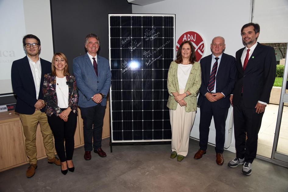 Autoridades y representantes de la empresa posan junto a un panel solar (de muestra)