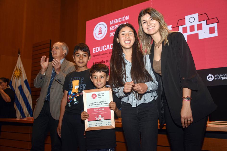 Mención especial: Escuela rural n.° 73 de Rincón de Vidal, Canelones Escolares y maestras sostienen diploma junto a autoridad