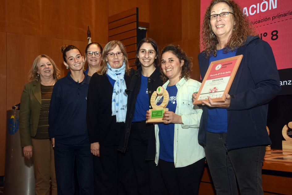 Ganador: Escuela n.° 8 de Salto (representantes) Ganadores sostienen un premio y un diploma junto a autoridad