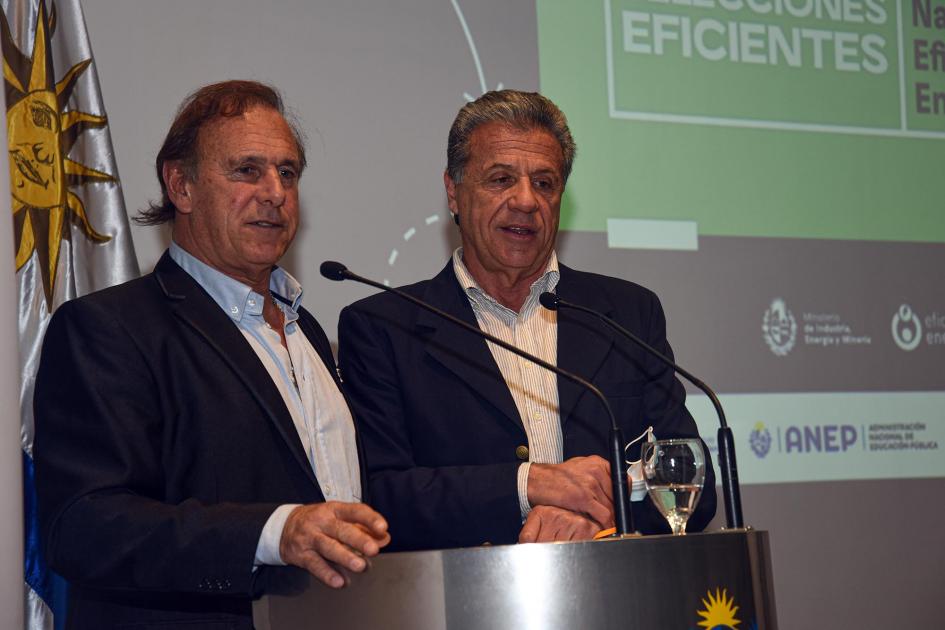 Los exfutbolistas Jorge Seré y Fernando Álvez presentaron el evento Fernando Álvez y Jorge Seré hablan en un atril; detrás, la bandera uruguaya