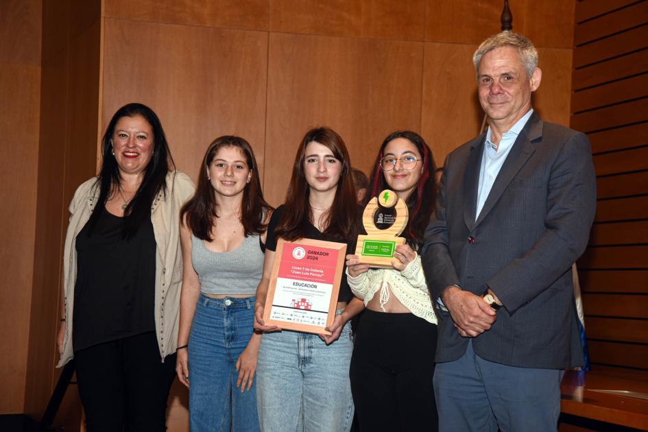 Ganador: Liceo n.° 1 de Colonia Juan Luis Perrou Ganadoras sostienen un premio y un diploma junto a una autoridad