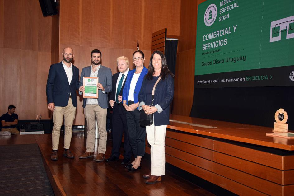 Mención especial: Grupo Disco Uruguay Ganadores sostienen un premio y un diploma junto a autoridad
