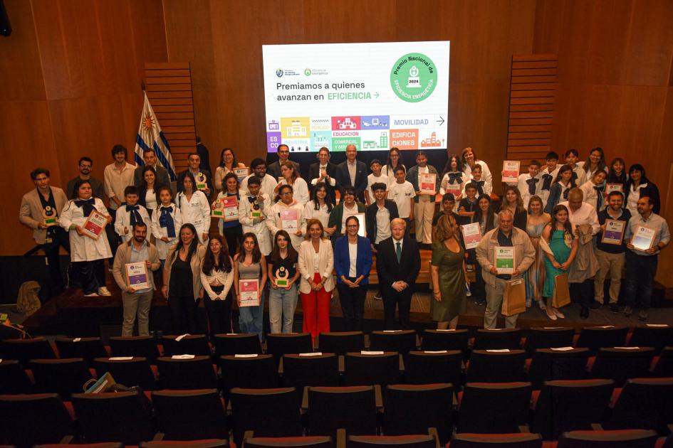 Ganadores del Premio Nacional de Eficiencia Energética 2024 Ganadores del premio y autoridades, sobre un escenario; detrás, pantalla y bandera nacional