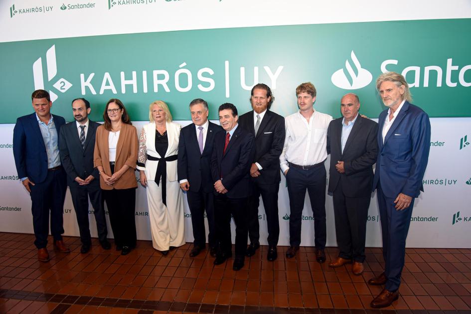 Autoridades e integrantes del proyecto Autoridades e integrantes del proyecto, de pie; detrás, banner con logos de Santander y Kahirós