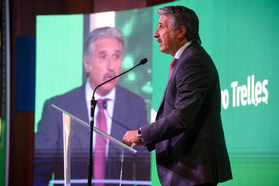 Country head del Grupo Santander, Gustavo Trelles Trelles habla desde un atril; detrás, pantalla con su nombre y una gran pantalla con su imagen