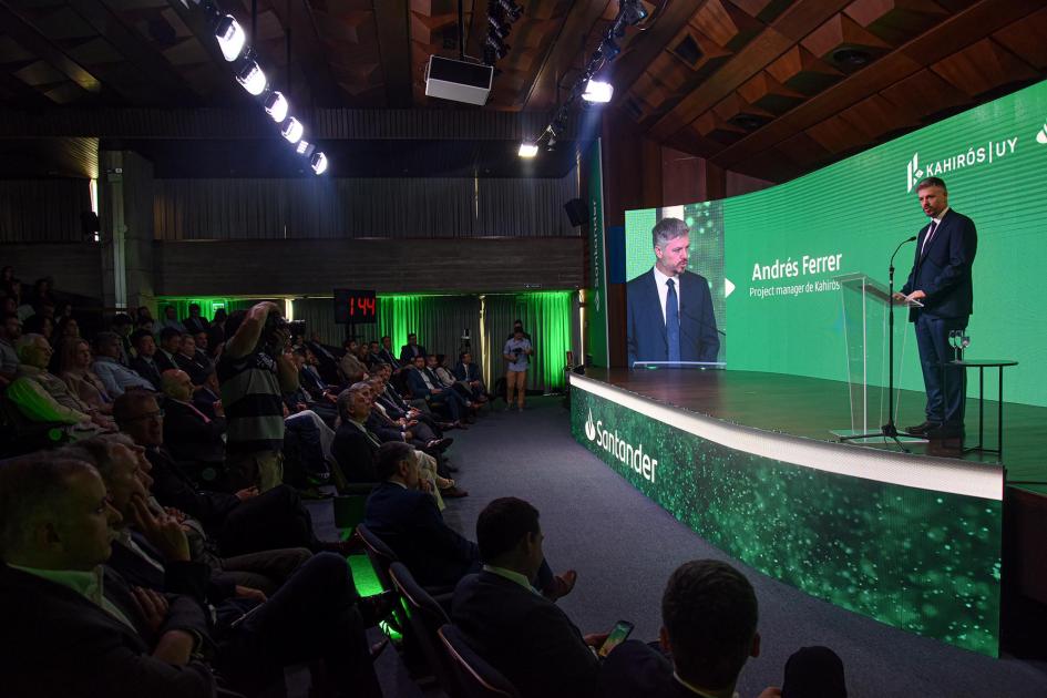 Project manager de Kahirós, Andrés Ferrer Ferrer habla desde un atril; detrás, pantalla con su nombre y su imagen; frente a él, público