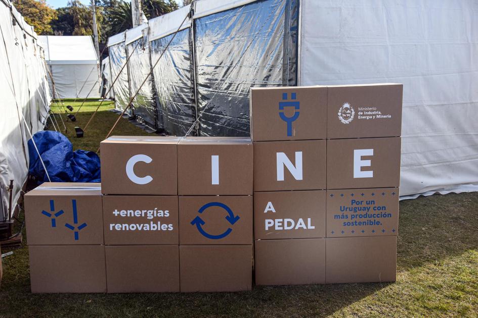 Cartel, hecho de un formato similar a cajas, en la puerta de la carpa del MIEM: dice Cine a Pedal