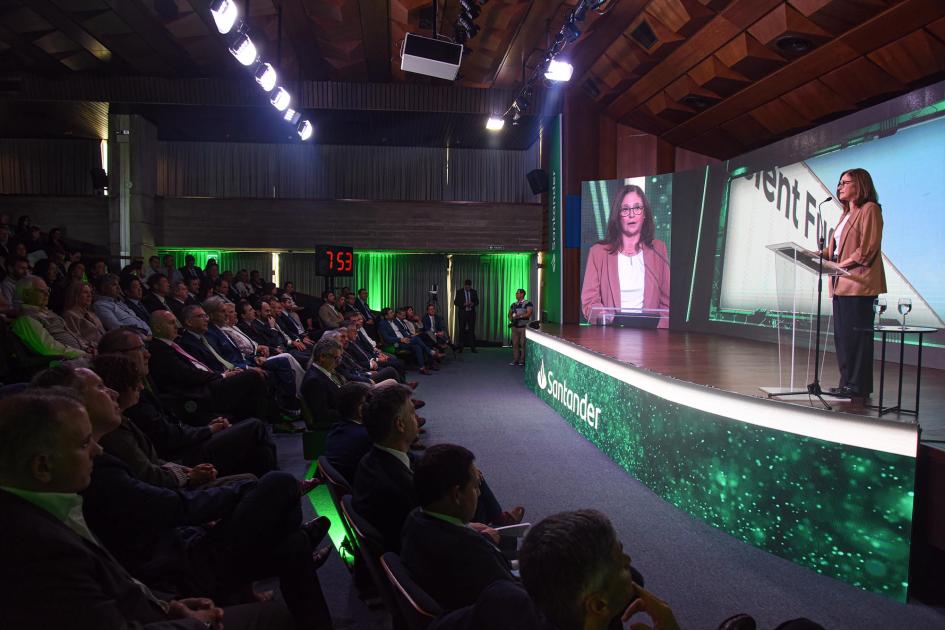 El evento se desarrolló en el auditorio del LATU Ministra habla en un escenario; al costado, pantalla con su imagen; frente a ella, público