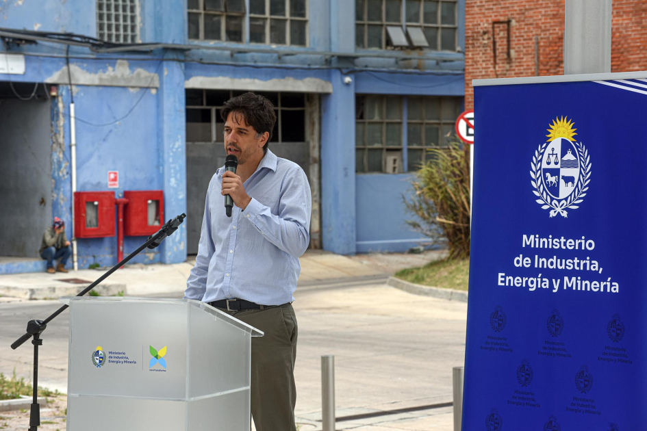 Un hombre habla desde un atril; al lado, banner del MIEM