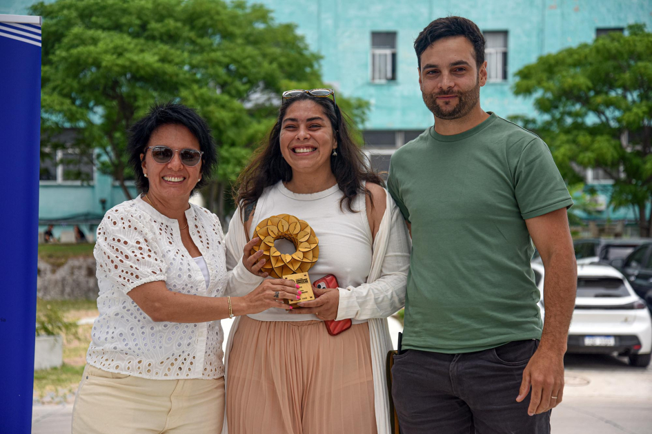Una mujer entrega un premio a una mujer y un hombre