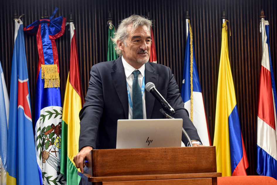 Pablo Ruiz Hiebra, coordinador residente en Uruguay de las Naciones Unidas Ruiz Hiebra habla en un atril; detrás, banderas