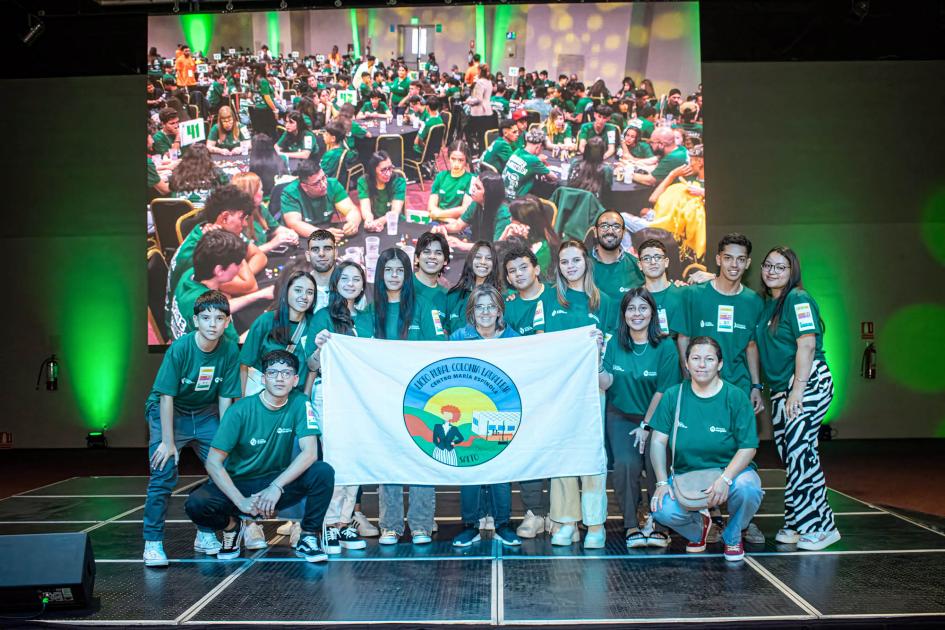 Adolescentes y docentes con una bandera que dice "Liceo Rural Colonia Lavalleja"