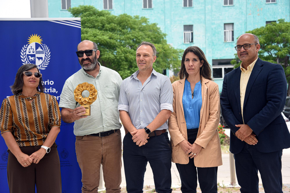 Varias personas sonríen; un hombre sostiene el premio