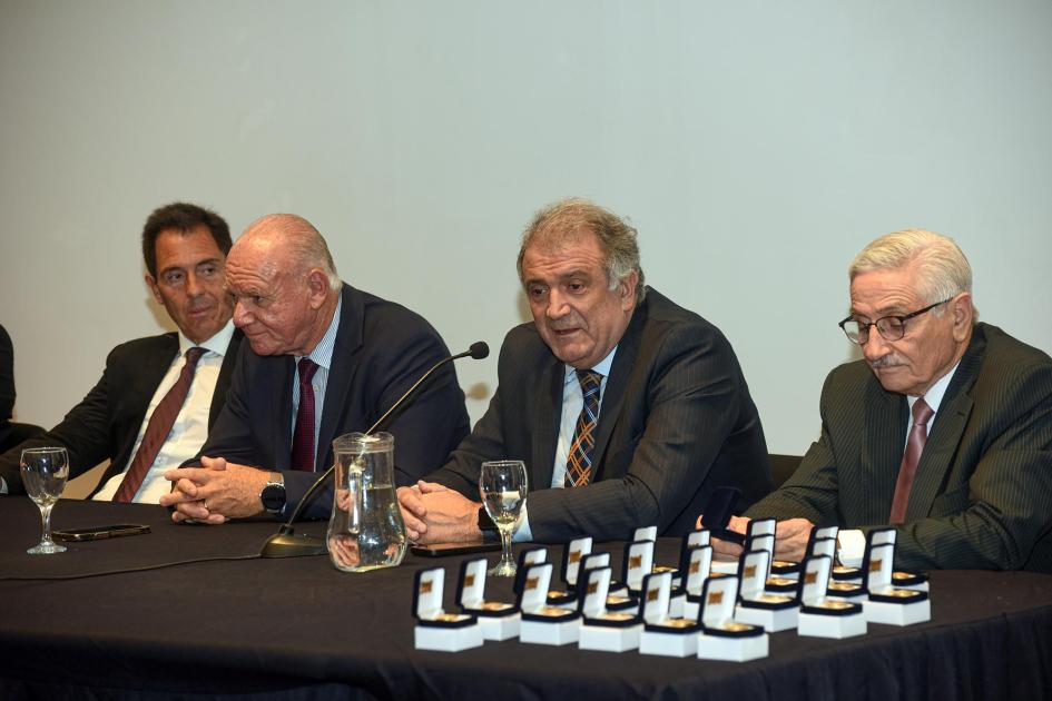 Osta habla en la mesa de autoridades; sobre ella, medallas para los funcionarios