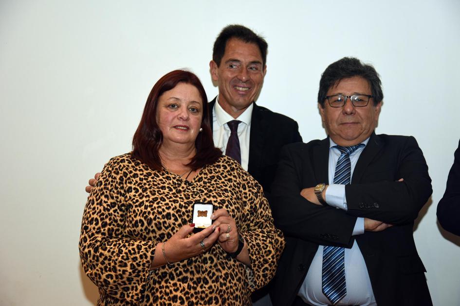 Trabajadora recibe un premio, junto a autoridades
