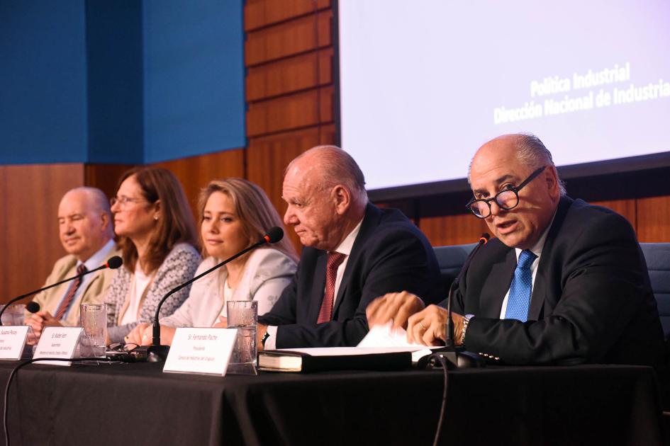 En la mesa de autoridades estuvo el presidente de la CIU, Fernando Pache Pache habla en la mesa de autoridades; está en un borde; detrás hay una pantalla