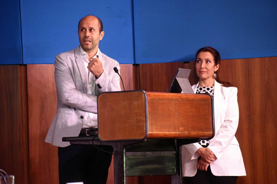 Funcionario de DNI Ángel Larrama presentó datos sobre el Fondo Industrial Funcionario de DNI habla desde un atril; detrás hay una mujer