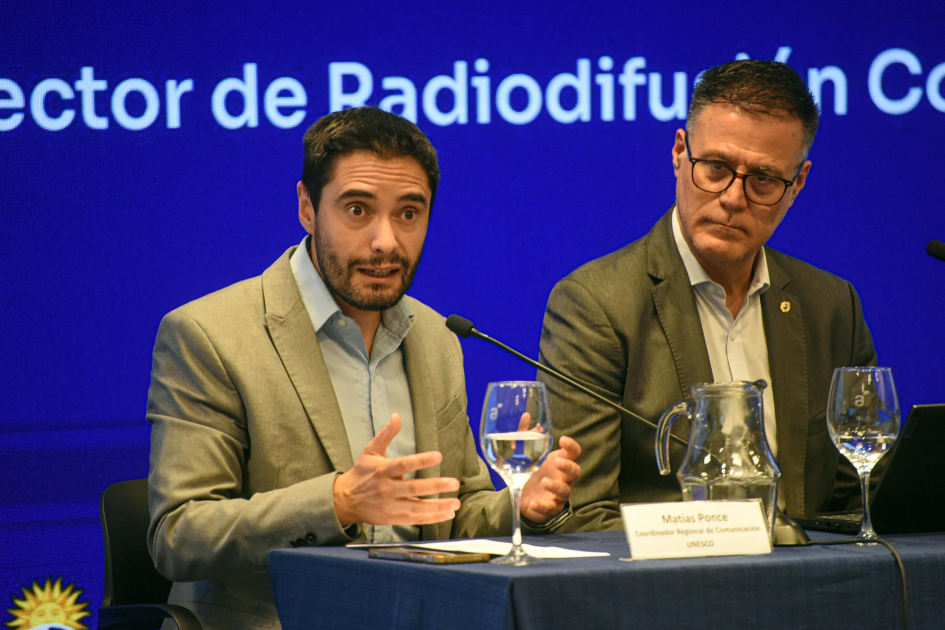 Matías Ponce y Pablo Siris. Detrás, pantalla azul con texto.