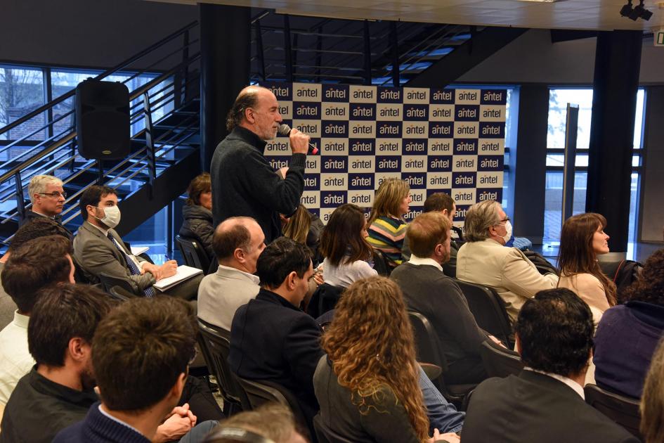 Integrantes del público realizaron preguntas al panel Un integrante del público, de pie, realiza una pregunta al panel; detrás se ve un banner de Antel