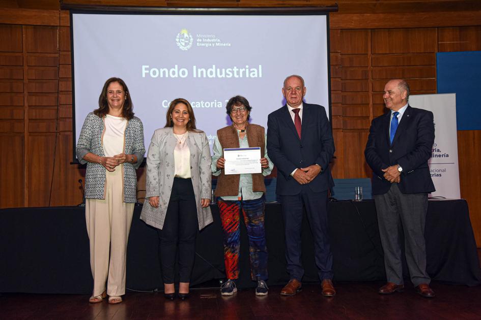 Premio para María Vittoria Saccarello (Pique Roto) Autoridades acompañan a una mujer que muestra su diploma; detrás hay una pantalla