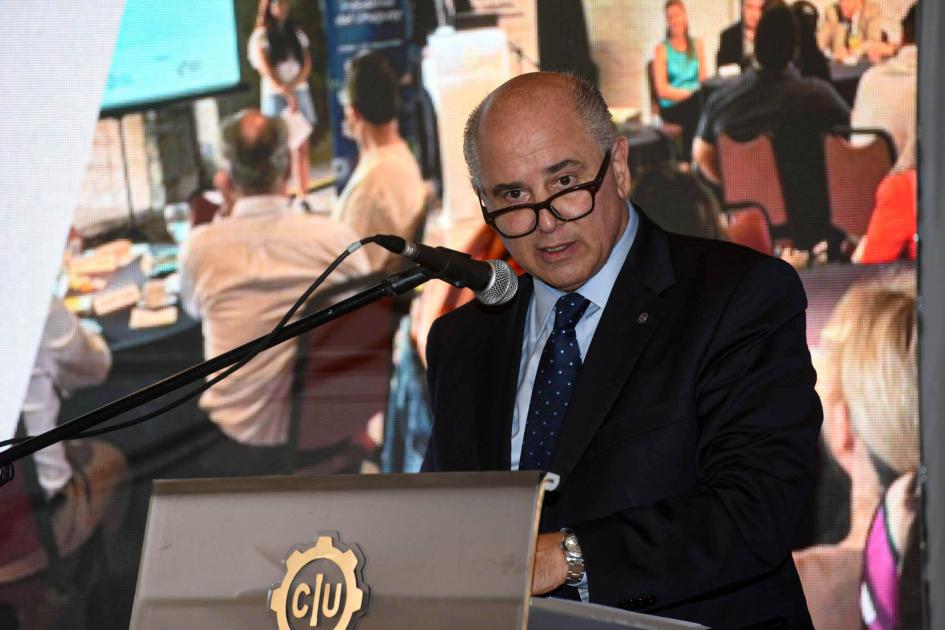 Presidente de la CIU, Fernando Pache Pache habla desde un atril; detrás, pantalla