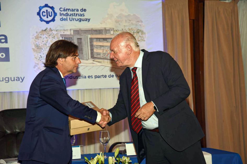 Saludo entre el presidente Luis Lacalle Pou y el ministro interino Walter Verri Lacalle Pou y Verri se dan la mano; detrás, pantalla
