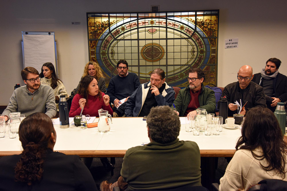 Asistentes, sentados en una mesa; detrás, vitral