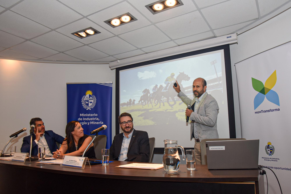 Expone Ángel Larrama de pie. Autoridades sentadas lo miran