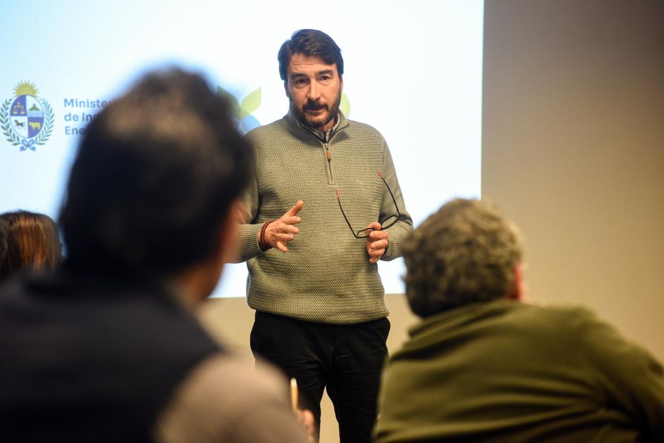 Míguez habla, de pie, a interlocutores sentados y de espaldas