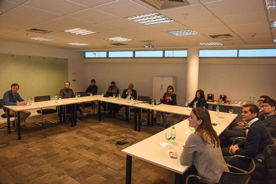 Los equipos del MIEM y Microsoft visitaron el Parque de las Ciencias Personas están sentadas en mesas en forma de "u"