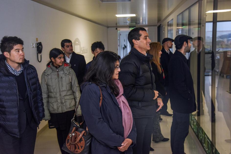 Varias personas están de pie, observando detrás de un vidrio