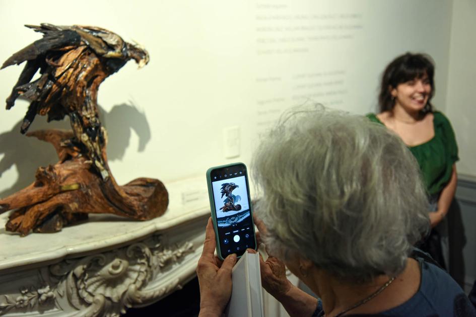 La exhibición puede visitarse hasta marzo de 2025 Una mujer saca una foto a una artesanía (pájaro de madera)